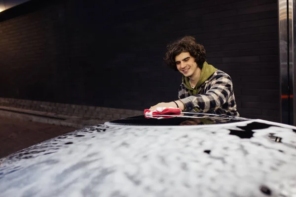 Happy man with detergent washing car in foam on self service wash — Stock Photo