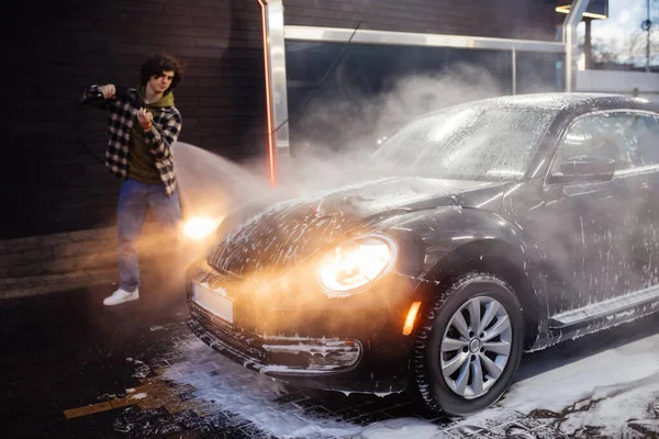 Car in foam near blurred driver with pressure washer outdoors — Stock Photo