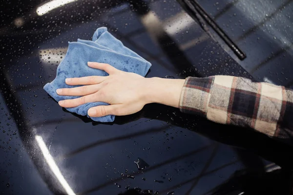 Vista cortada do homem com pano de limpeza carro preto — Fotografia de Stock