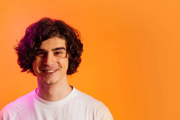 Curly man smiling at camera isolated on orange — Stock Photo