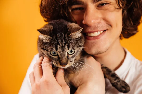 Gatto in mano di uomo sfocato sorridente isolato su arancione — Foto stock