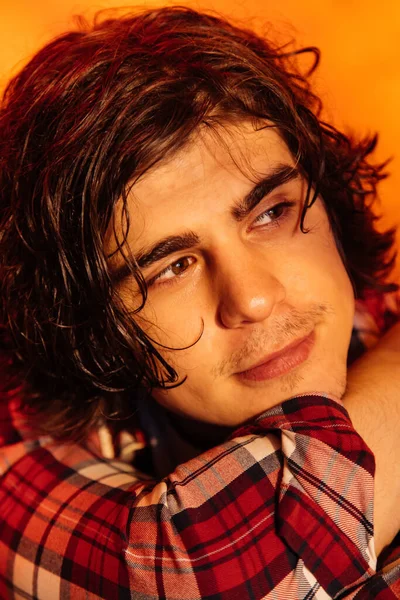 Portrait of young curly man in plaid shirt isolated on orange — Stock Photo