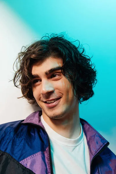 Young man with curly hair smiling on white and blue background — Stock Photo