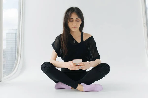 Brünette armenische Frau, die mit überkreuzten Beinen auf dem Handy sitzt — Stockfoto