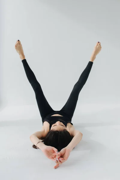 Barefoot armenian woman in black leggings practicing yoga in rejuvenation pose on white — Stock Photo