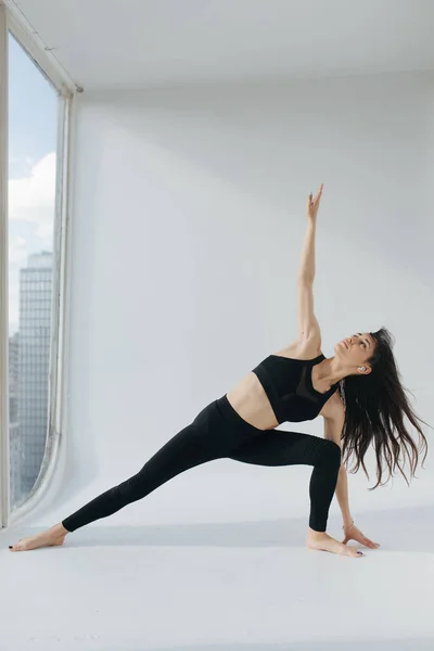 Morena mulher arménia praticando corredores twist pose no chão branco em casa — Fotografia de Stock