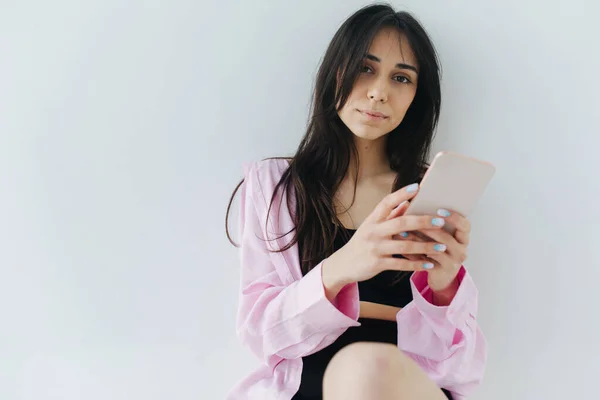 Junge armenische Frau mit Smartphone blickt auf Kamera auf weißem Hintergrund — Stockfoto
