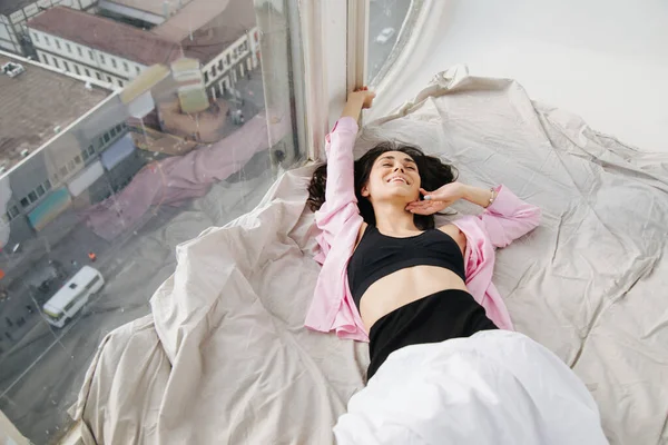 High angle view of happy armenian woman stretching on white bedding near window — Stock Photo