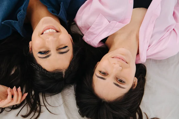 Vue de dessus de deux femmes arméniennes gaies souriant à la caméra tout en étant couché ensemble — Photo de stock