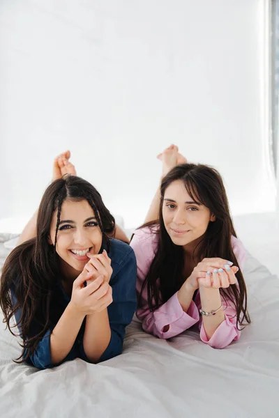 Jeunes et heureuses femmes arméniennes souriant à la caméra alors qu'elles étaient allongées sur une literie blanche — Photo de stock