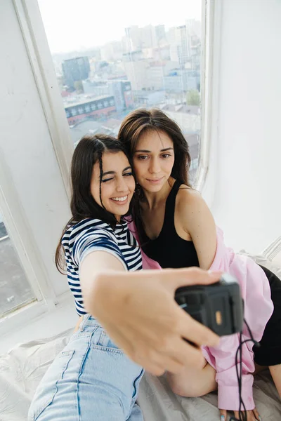 Heureux arménienne femme prendre selfie avec ami sur appareil photo numérique près de la fenêtre — Photo de stock