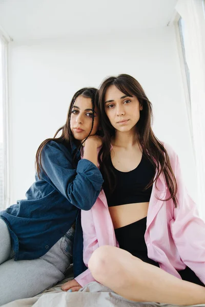 Young armenian woman leaning on shoulder of friend while sitting on bedding — Stock Photo