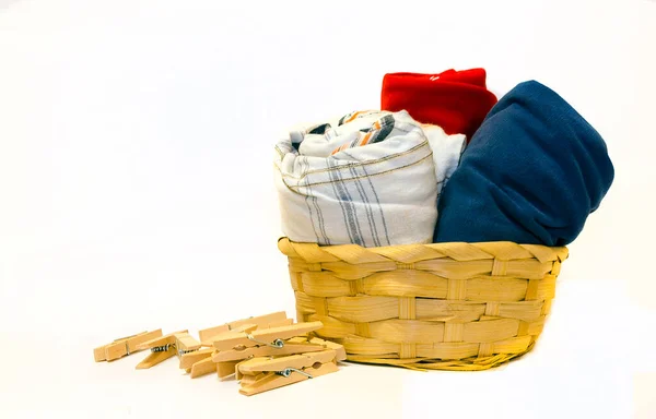 Hasır sepetteki renkli giysiler beyaza izole edilmiş.