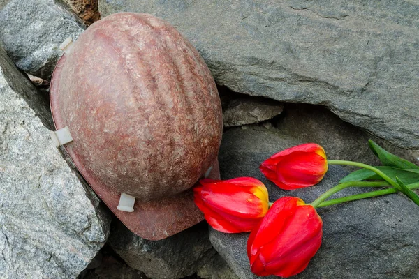 Madenci miğferi. Madencilerin ölümünün anısı. Taşlardaki çiçek laleleri.