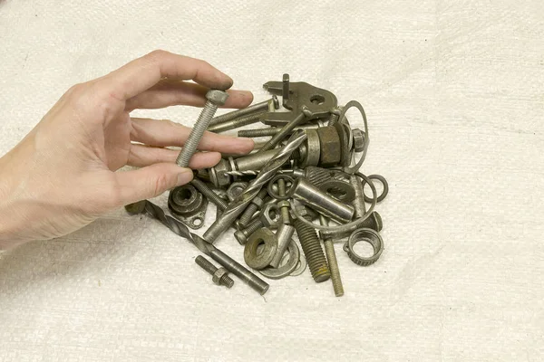 Eski paslı hurda metal, kullanılmış parçalar ve alet parçaları. El sürgüyü tutar. Bir sürü küçük demir parçası. Onarım.