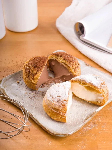 Tabağa konmuş Choux kremi, kahverengi ahşap arka plan.