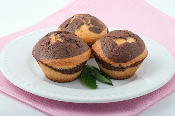 Beyaz bir plaka üzerinde üç lezzetli muffins