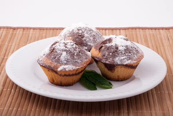 Beyaz bir plaka üzerinde üç lezzetli muffins