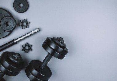 Siyah halterlerin ve gri arka planda halterlerin üst görüntüsü. Düz yatıyordu. Fitness ya da vücut geliştirme sporu eğitimi konsepti. Boşluğu kopyala.