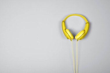 Gri arka planda sarı kulaklıkların üst görüntüsü. Düz yatıyordu. Uzayı kopyala Moda renkleri 2021.