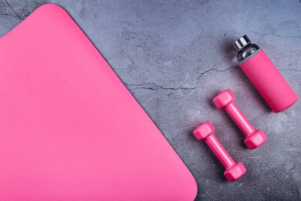 Ovanifrån på träningsmatta, glasflaska och rosa hantlar i marmorgrått — Stockfoto