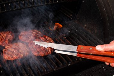 Kızarmış et, barbekü köftesi, hamburgerler için metal maşalar, çatal bıçaklar, ızgara ızgara üzerine..