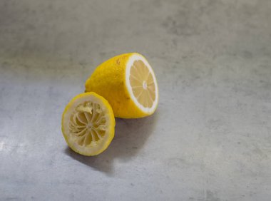 Limon yarıları gri mermer tezgahta duruyor. Sol bölüm bölümleri, çekirdekleri ve buruşuk iç kısımları sıkıştırarak açığa çıkarır. Ayarlama basit. Düzen bozulmadan kalır..