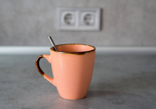 Cup coffee placed on gray countertop. Soft light covers scene. Double kitchen outlet appears behind items. Objects arranged without extra feature or decoration. Visual display remains simple, factual.