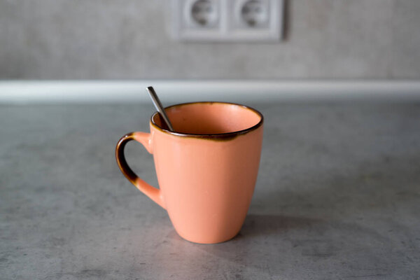 Cup coffee placed on gray countertop. Soft light covers scene. Double kitchen outlet appears behind items. Objects arranged without extra feature or decoration. Visual display remains simple, factual.