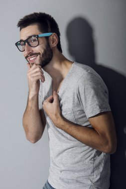 Man with beard dressed casual smiling against gray wall
