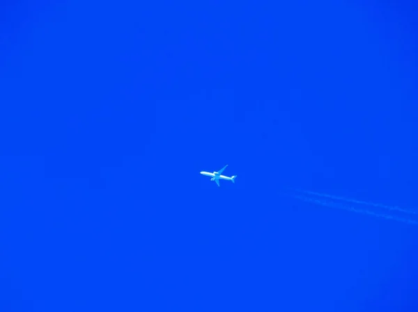 Avión con estelas químicas en el cielo azul — Foto de Stock