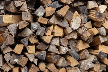 a lot of dry old chopped wood is stacked in a woodpile