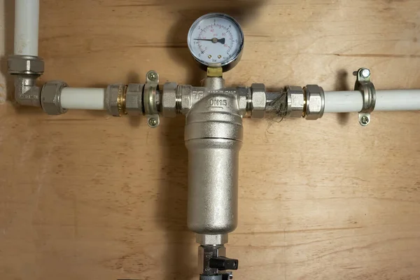large metal filter for water purification with a pressure gauge at home close-up. the filter is made of nickel-plated brass