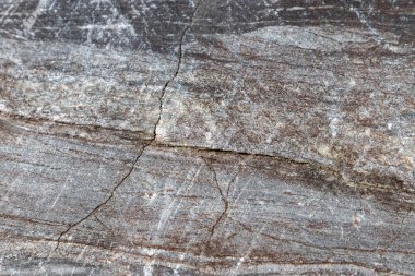 Gri-kahverengi mermer desenli, parlak güneş ışığı altında bir çatlak.