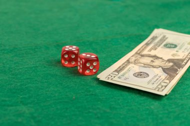 iki kırmızı zar ve bir yığın dolar yeşil bir kumaşa.