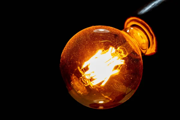 Decorative carbon filament bulb light. Dust on the glass. Macro photography.