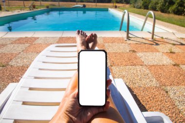 Havuz başında elinde cep telefonuyla tatilde olan bir kadın.