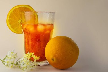 Portakal suyu ve buzlu büyük bardak. Bej arka planda bir portakal.