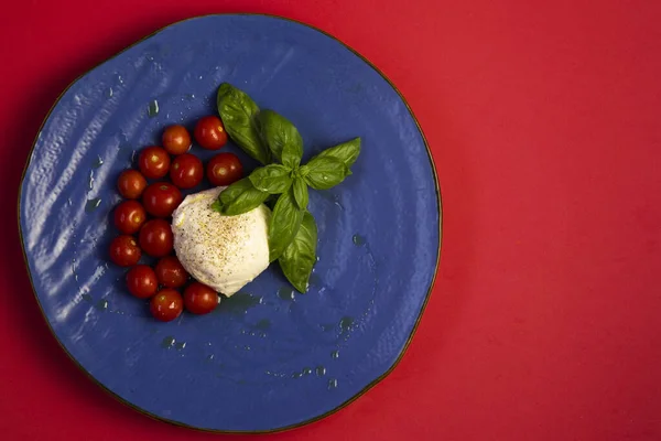 Mozzarella Cherry Rajčata Bazalka Modrém Talíři Červeném Pozadí — Stock fotografie
