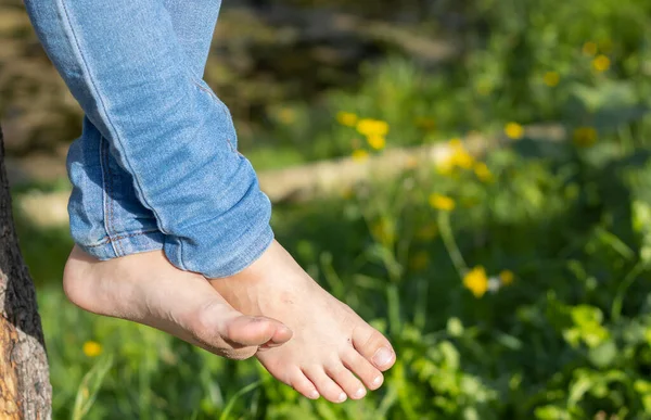 girl\'s bare feet hanging over green grass