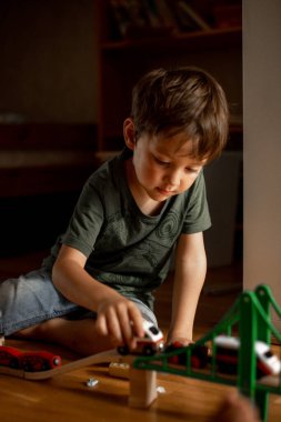 Küçük çocuk 5 yaşında, evde ahşap demiryolu oynuyor. çocuk oyuncaklarla oynuyor