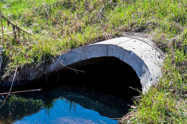 Volledige capaciteit beton duiker met glanzende verontreinigde storm water runoff — Stockfoto