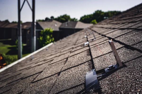 집에 있는 아스팔트 지붕에는 태양열 패널 레일 과 레이킹 시스템을 설치하기 위해 설치 된 금속 앵커가 설치되어 있다 — 스톡 사진