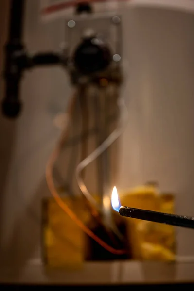 Met behulp van een aansteker om de piloot op een warmwaterverwarmingstoestel te laten branden — Stockfoto