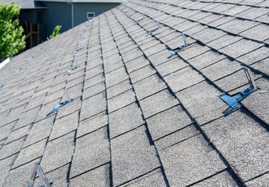 Yerleşik asfalt kiremit çatısında güneş paneli demiryolu ve rampa sistemi kurmak için metal çapalar yerleştirildi