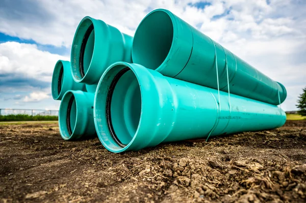 Stacked water main pipe with bell fitting next to an exposed trench for installation — Stock Photo, Image