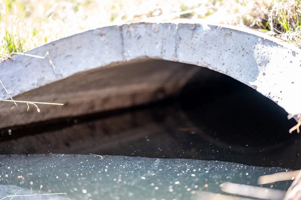 Bueiro de concreto de plena capacidade com escoamento de águas pluviais contaminadas por brilho — Fotografia de Stock