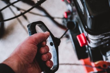 Kar püskürtücüsünde veya çim biçme makinesinde taşınabilir motor çalıştırmak için kabloyu çekin