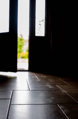 Fayans zemininde görünen küçük çocuk ayak izleri. Açık bir kapı var. Arka planda ışık var.