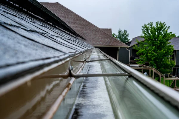 Selectieve focus op een deel van residentiële dakgoot met hanger die water transporteert tijdens een storm. Regenspetters en -druppels zichtbaar. — Stockfoto